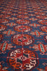 Load image into Gallery viewer, A close-up of a patterned textile or rug with a blue background and repeating red, orange, cream, and black geometric medallion motifs.