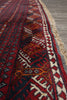 Load image into Gallery viewer, A close-up of a patterned rug showing deep red, navy blue, cream, and orange geometric motifs with a fringed edge, laid on a gray wooden floor.