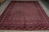 Load image into Gallery viewer, A large traditional Persian-style area rug with a dark navy blue field, red and orange floral motifs, and a detailed geometric border, laid out on a gray concrete floor.