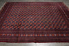Load image into Gallery viewer, A large rectangular area rug with a dark navy blue field, repeating red and orange floral medallions, and a patterned border, laid flat on a gray tiled floor.