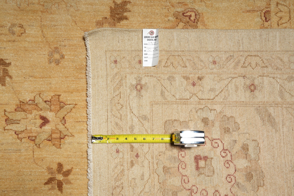 A close-up of a beige patterned area rug with a white tag and a yellow tape measure laid across it for scale, placed on top of a matching beige rug background.