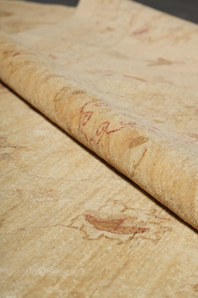 A close-up of a rolled beige stone or marble-look material with natural tan and reddish-brown veining, shown against a matching flat surface.