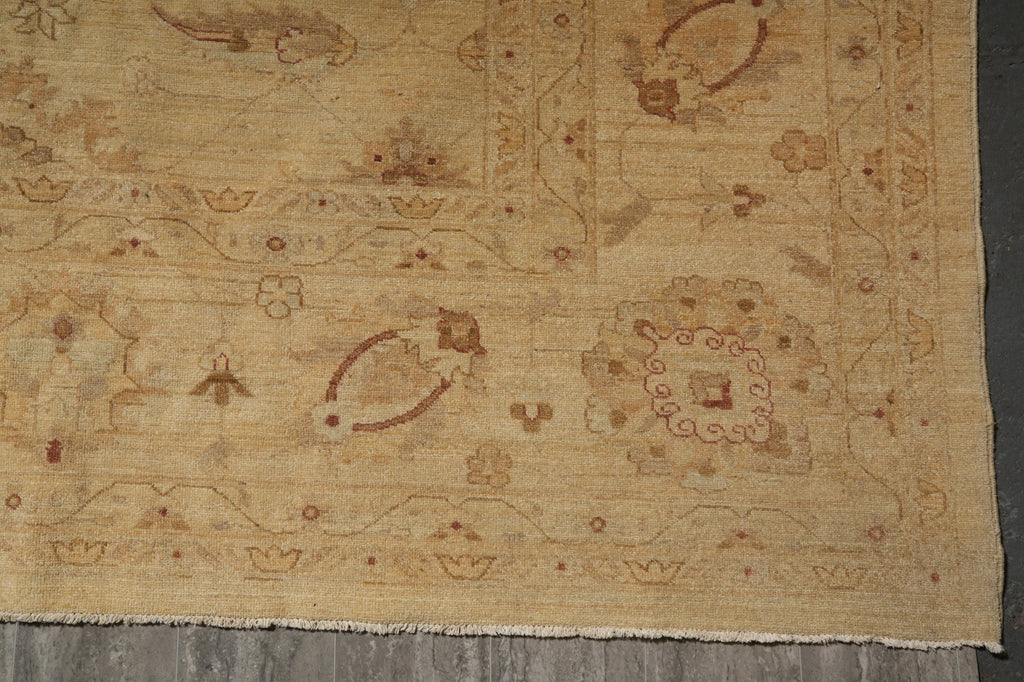 A close-up of a vintage-style area rug with a faded beige and brown floral pattern, laid out on a dark floor.