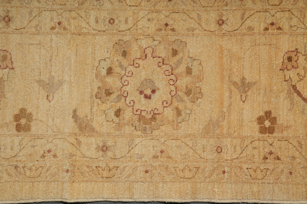 A close-up of a vintage-style area rug with a central medallion and floral motifs in warm beige, tan, and muted reddish-brown tones.