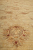 Load image into Gallery viewer, A close-up of a light beige rug with a faded sunburst motif in muted brown and reddish accents.