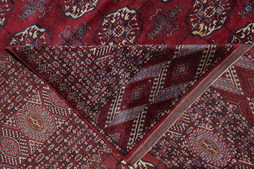 A close-up of a patterned area rug with deep red, navy, beige, and brown geometric and floral motifs.
