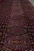 Load image into Gallery viewer, A close-up view of a patterned rug with repeating geometric and floral motifs in deep red, navy, beige, and orange tones.