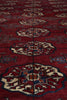 Load image into Gallery viewer, A close-up of a red patterned rug with repeating medallion motifs in cream, blue, and rust tones.