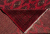 Load image into Gallery viewer, A close-up of a folded red patterned rug or textile showing a dark red geometric border, cream fringe, and a repeating medallion motif in red, black, and brown.