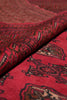 Load image into Gallery viewer, A close-up of a folded red patterned rug showing its woven texture and traditional geometric motifs in red, black, and beige.