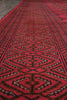 Load image into Gallery viewer, A close-up view of a red patterned rug with geometric tribal designs in black and beige, shown in perspective.