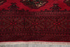 Load image into Gallery viewer, A close-up of a traditional patterned rug with a deep red field, black geometric borders, and light beige fringe at the bottom.