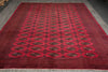 Load image into Gallery viewer, A large red oriental area rug with a repeating geometric pattern and dark borders, laid out on a gray floor.