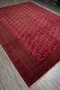 Load image into Gallery viewer, A red Persian-style area rug with intricate dark brown and black geometric patterns and borders, laid out on a gray wood floor.