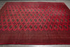 Load image into Gallery viewer, A large red oriental rug with an intricate repeating geometric and floral pattern in dark brown and black, laid out flat on a gray tiled floor.