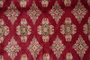 Load image into Gallery viewer, A close-up of a red patterned rug or fabric with repeating ornate medallion motifs in beige, cream, black, and muted blue.