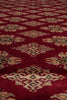 Load image into Gallery viewer, A close-up of a red patterned rug or textile with repeating diamond motifs in beige, black, and muted green.
