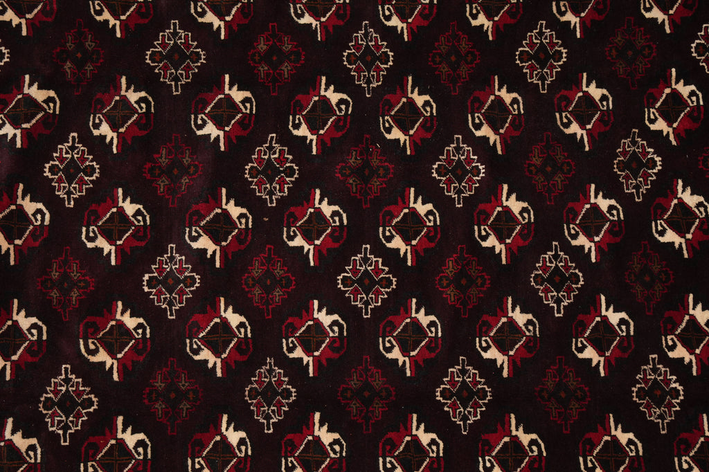 A close-up of a patterned fabric or wallpaper featuring a repeating geometric and floral motif in red, beige, and black.