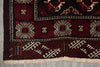 Load image into Gallery viewer, A close-up of a traditional patterned rug corner, showing a dark red and black field with cream and red geometric motifs, a decorative border, and cream fringe.