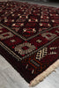 Load image into Gallery viewer, A close-up of a traditional patterned rug with a deep red and black base, cream and brown geometric motifs, and a fringed edge, laid on a light gray tiled floor.