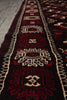 Load image into Gallery viewer, A close-up view of a traditional oriental runner rug with a dark red and black base, featuring cream and red geometric patterns and motifs.