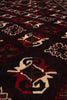 Load image into Gallery viewer, A close-up of a patterned rug with a dark brown or near-black base, featuring red and cream geometric and floral motifs.