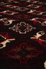 Load image into Gallery viewer, A close-up of a patterned textile or rug with a dark base and repeating geometric motifs in red, cream, and black.