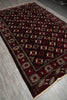 Load image into Gallery viewer, A dark red and black patterned area rug with beige geometric borders and motifs, laid out diagonally on a gray tiled floor.