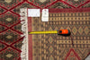 Load image into Gallery viewer, A patterned area rug with cream fringe is shown laid flat on a matching patterned surface, with a yellow tape measure and price tag visible along the left edge to indicate size and condition.