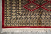 Load image into Gallery viewer, A close-up of a patterned rug corner showing cream, red, and black geometric motifs with white fringe tassels on a gray floor.