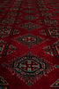 Load image into Gallery viewer, A close-up of a red patterned rug with traditional geometric medallions in black, green, and beige.
