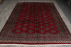 Load image into Gallery viewer, A rectangular red oriental rug with a traditional geometric pattern and fringed edges, laid out on a gray wood floor.