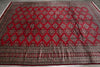 Load image into Gallery viewer, A large red oriental area rug with a detailed geometric diamond pattern and a decorative border, laid flat on a gray wood floor.