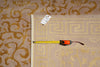 Load image into Gallery viewer, A beige area rug with a yellow Greek key pattern and a white border, shown with a yellow tape measure and a white tag on top of it, placed next to a matching patterned rug.