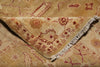 Load image into Gallery viewer, A close-up of a patterned area rug with a folded corner showing the fringed edge. The rug has a warm beige and tan base with dusty red and muted brown geometric and floral motifs.