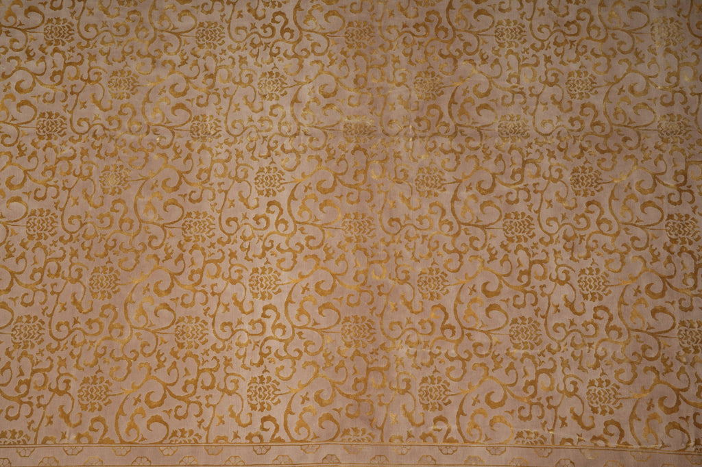 Beige damask fabric with an intricate gold floral and scroll pattern, featuring a decorative border along the bottom edge.