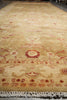 Load image into Gallery viewer, A long rectangular area rug with a distressed traditional pattern in beige, cream, and muted red, featuring a fringed edge and photographed from a high angle.