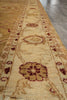 Load image into Gallery viewer, A close-up view of a traditional area rug with a beige and cream base, featuring a central border and floral motifs in rust red and brown, shown on a dark wood floor.
