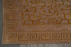 Load image into Gallery viewer, Close-up of a patterned area rug corner showing a beige and gold floral design with a Greek key border on a gray floor.