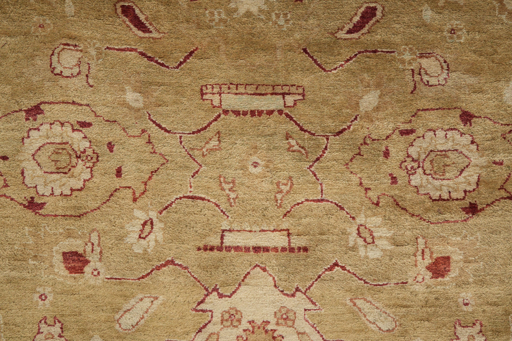 A close-up of a traditional patterned rug with a warm beige background and muted red and cream floral motifs.