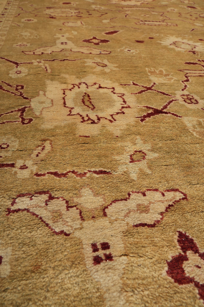 A close-up view of a traditional area rug with a beige and cream base and dark red/burgundy floral motifs.
