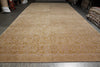Load image into Gallery viewer, A large rectangular area rug laid out in a warehouse or showroom, featuring a warm beige and tan floral pattern with a Greek key border.