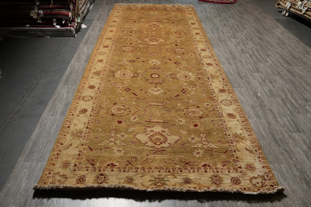 A long rectangular area rug with a traditional medallion pattern in beige, brown, and muted red, laid out on a gray wood-look floor.