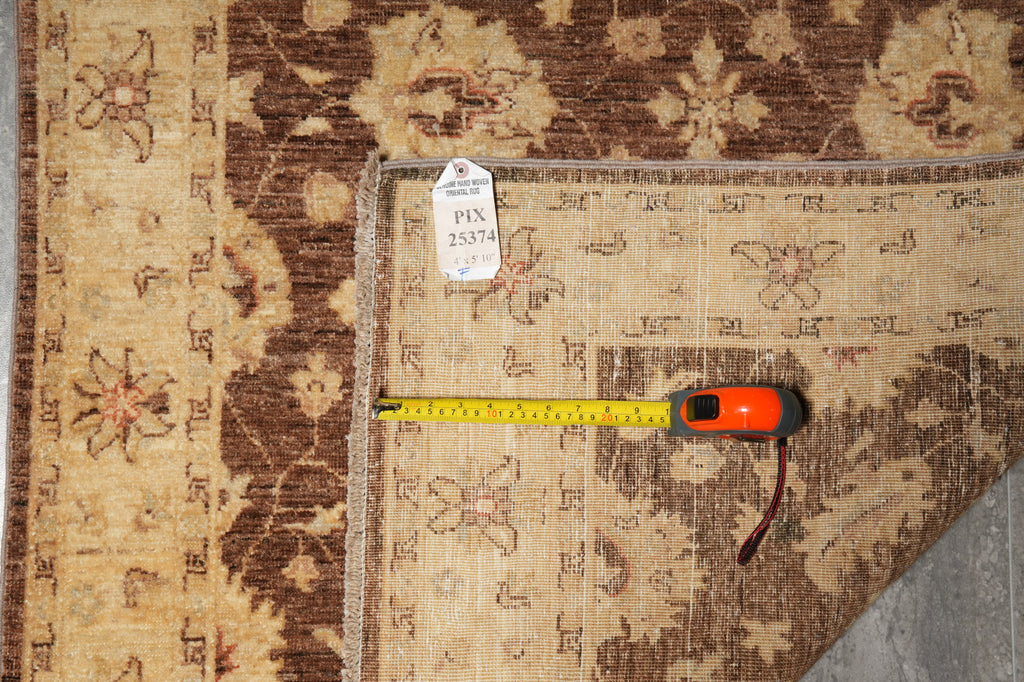 An overhead view of a patterned area rug with a yellow tape measure and a white inventory tag placed along the corner to show dimensions.