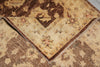 Load image into Gallery viewer, A close-up of a traditional area rug with a folded corner revealing its pattern and fringed edge. The rug features a distressed, vintage-style design in shades of brown, beige, and muted orange.