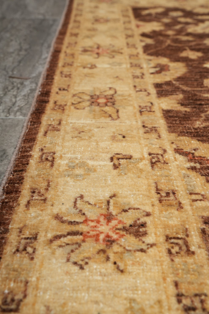 Close-up of a woven rug or textile with a beige and brown patterned border featuring floral motifs and repeating geometric details.