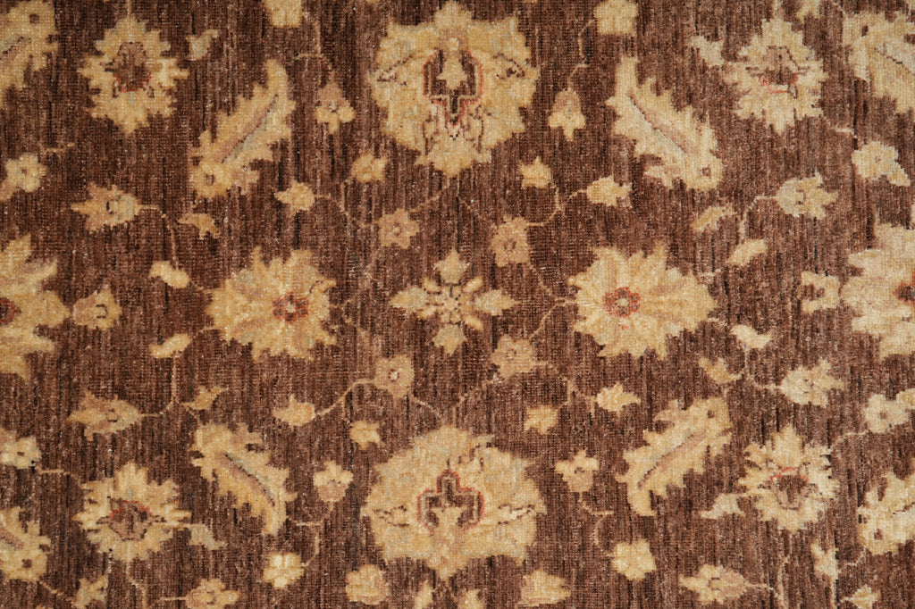 A close-up of a traditional patterned rug with a dark brown background and cream floral motifs.