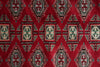 Load image into Gallery viewer, A close-up of a red patterned textile or rug featuring repeating geometric diamond motifs in beige, black, and muted blue-gray.