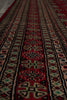 Load image into Gallery viewer, A close-up view of a patterned rug with horizontal bands of red, black, beige, and small turquoise accents in a geometric and floral design.