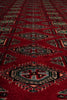 Load image into Gallery viewer, A close-up of a red patterned rug with geometric and tribal-style motifs in black, beige, and muted green.
